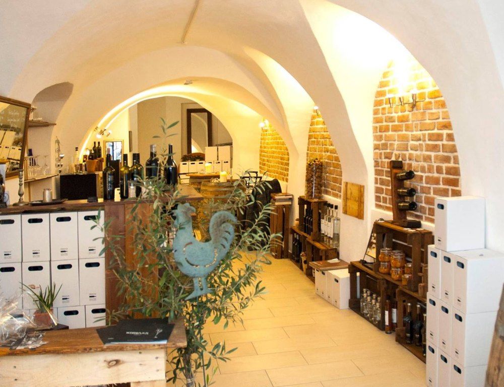 Pohled do interiéru vinárny s cihlovými stěnami a lahvemi vína.