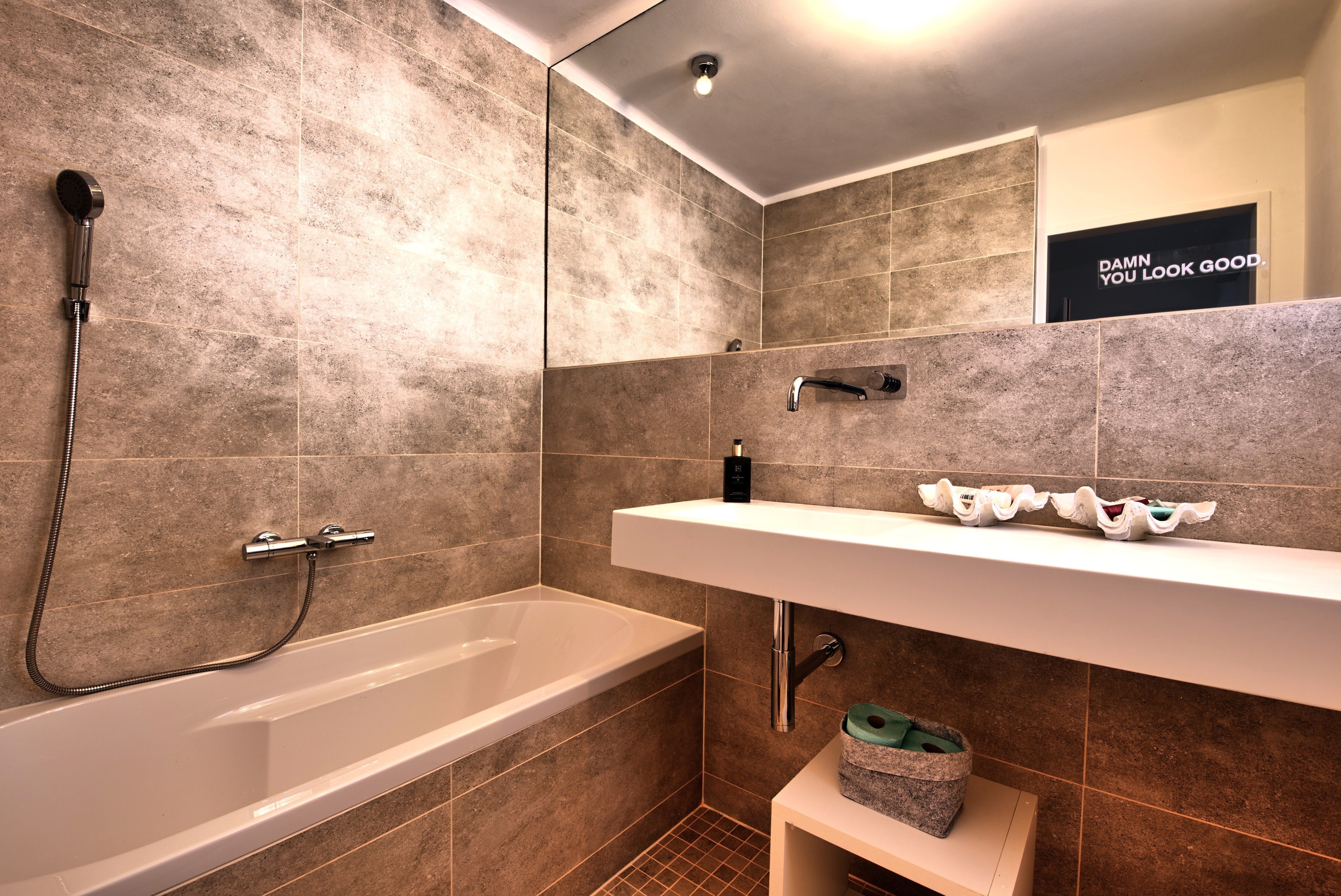 Moderní koupelna s vanou, umyvadlem a velkým zrcadlem.