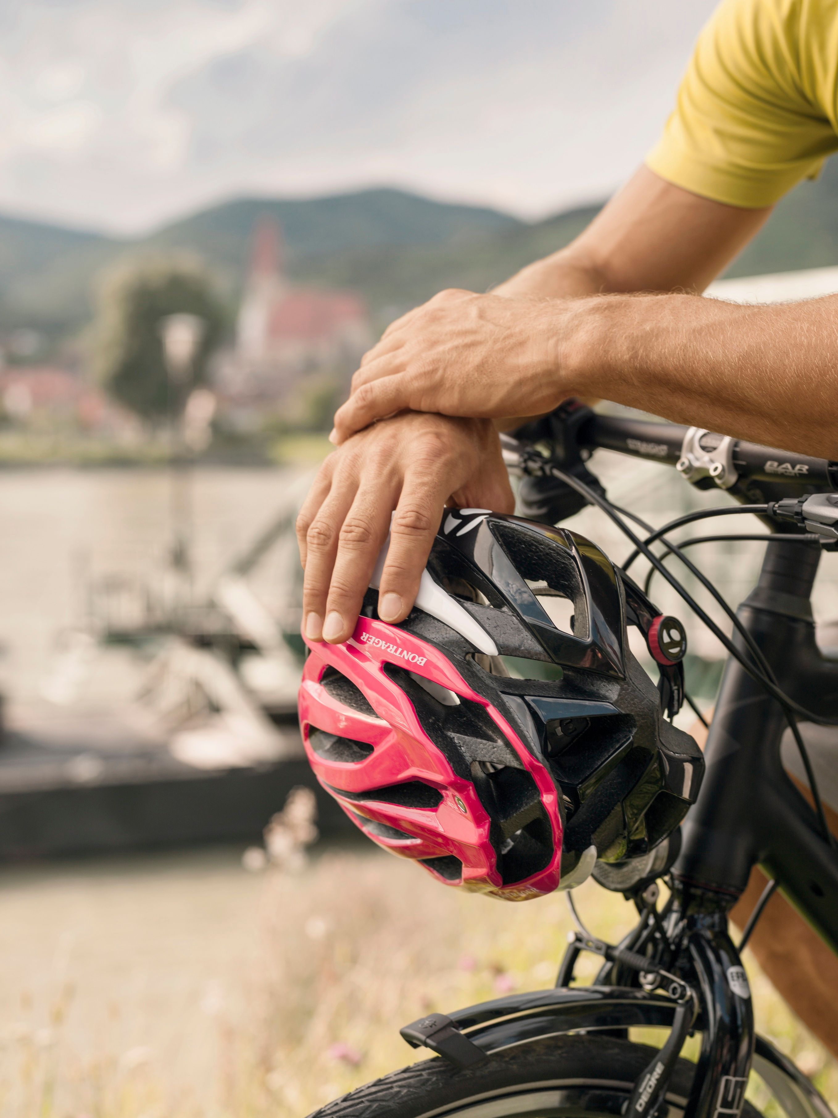 Dvě ruce držící cyklistickou přilbu na řídítkách jízdního kola
