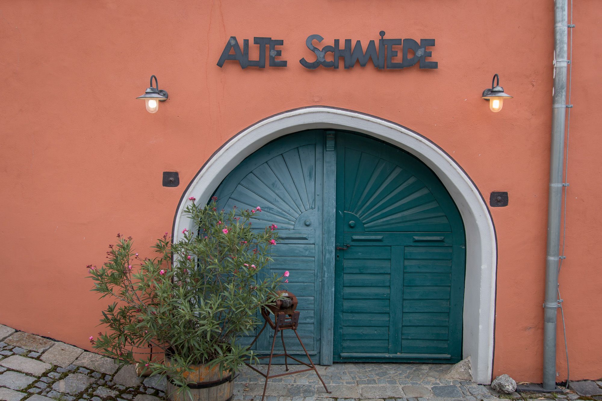 Stará brána s nápisem "Alte Schmiede" a rostlinami před ní.