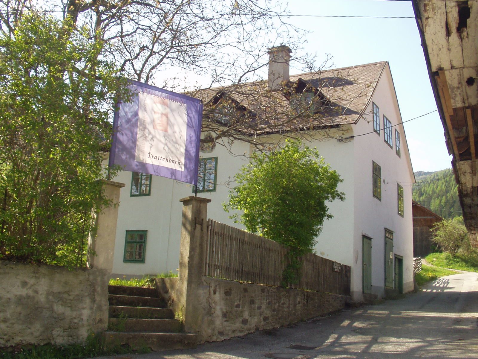 Bílá budova se zelenými okenními rámy a nápisem "Trattenbach".