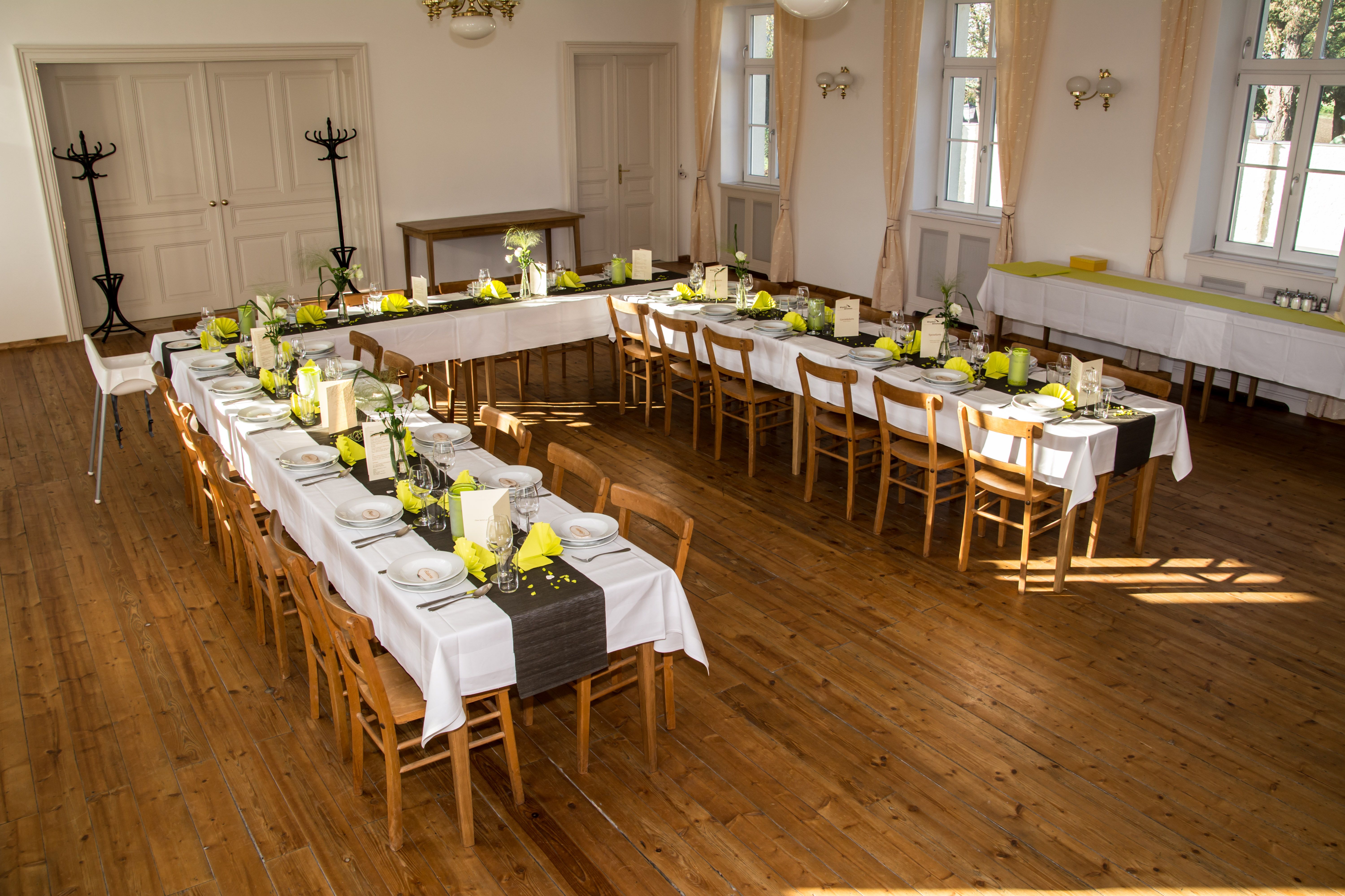 Slavnostně vyzdobený sál s dlouhými stoly a žlutými ubrousky.