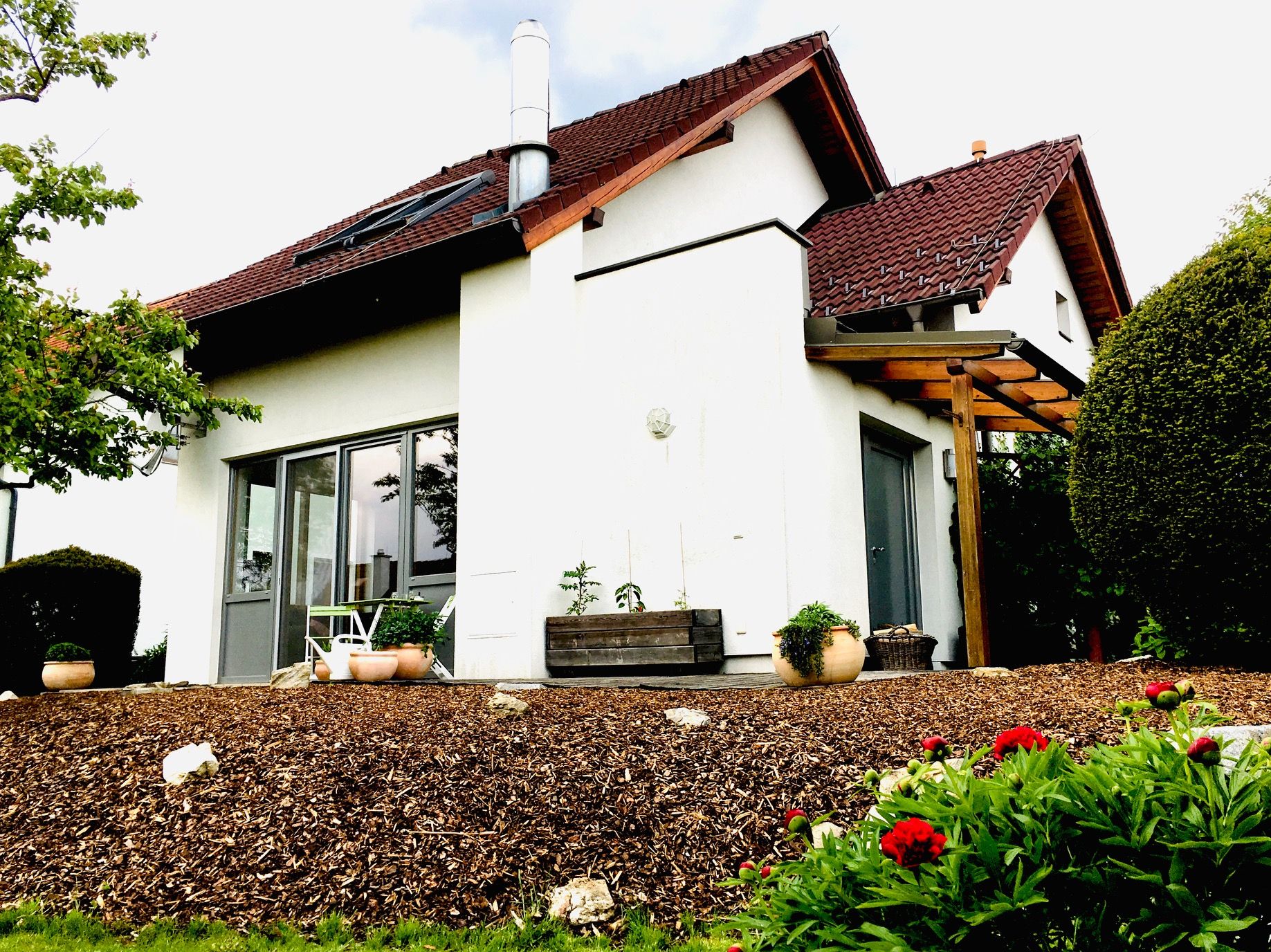 Pohled zvenčí na moderní rodinný dům se zahradou a terasou.