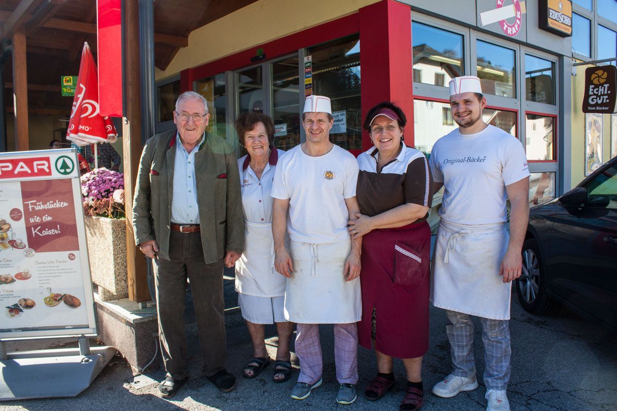 Pět lidí stojí s úsměvem před vchodem do obchodu.