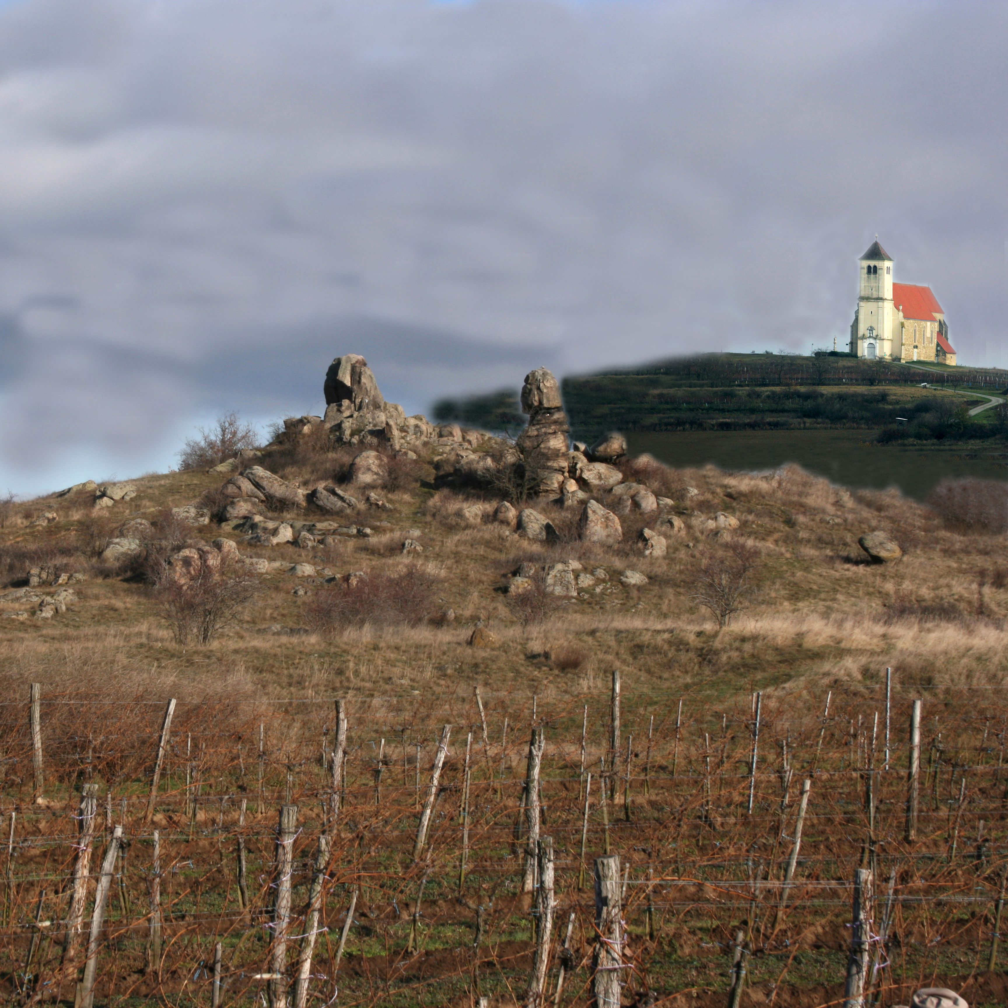 Krajina se skalními útvary a kostelem v pozadí.