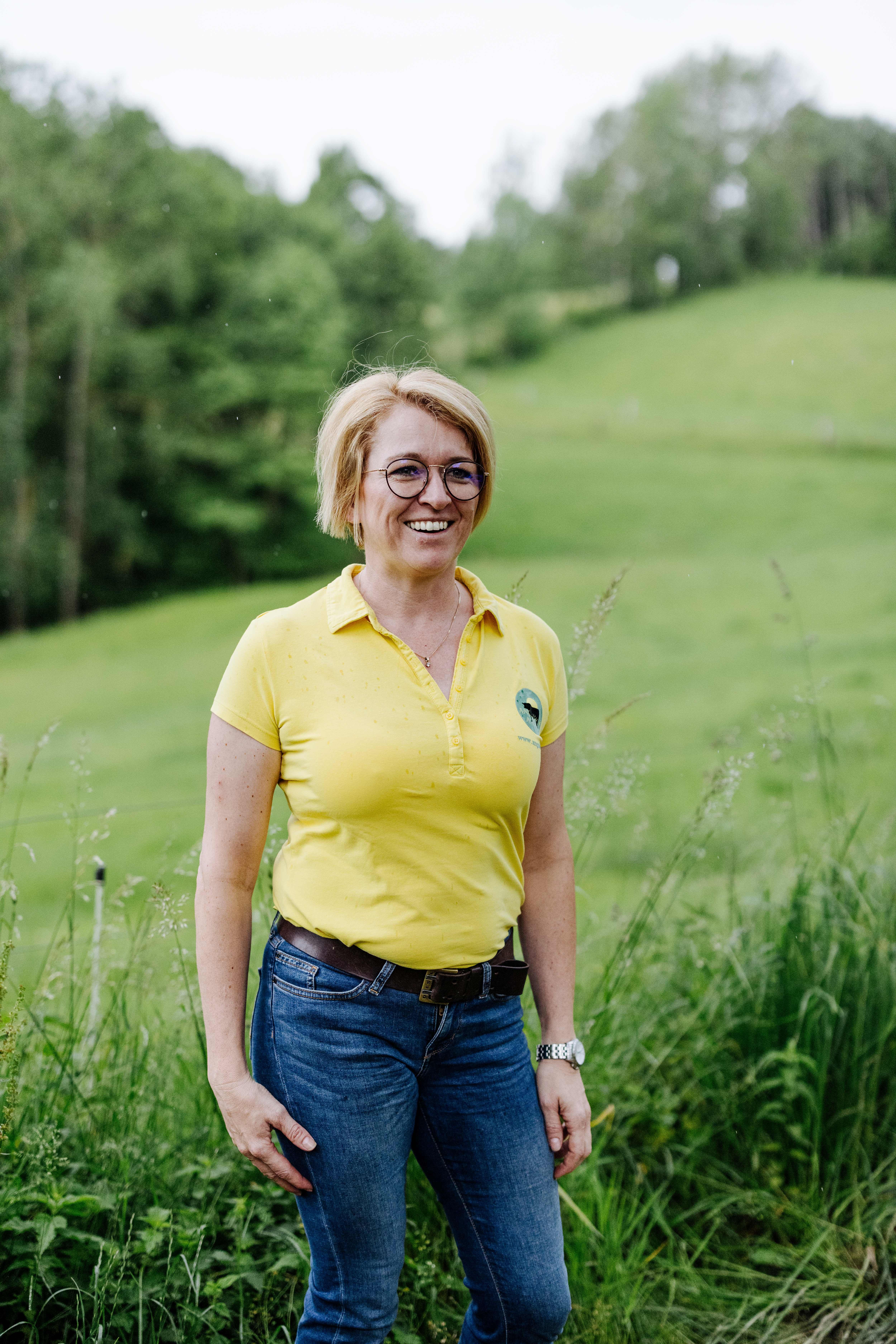 Majitelka Sandra Anderlová stojí s úsměvem na zelené louce.