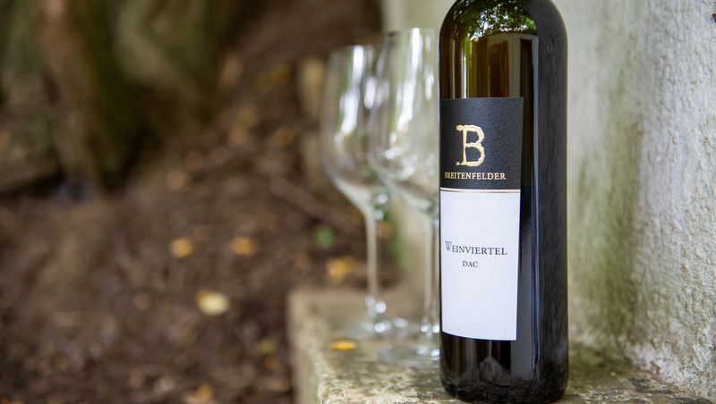 Láhev vína se dvěma prázdnými sklenicemi venku.