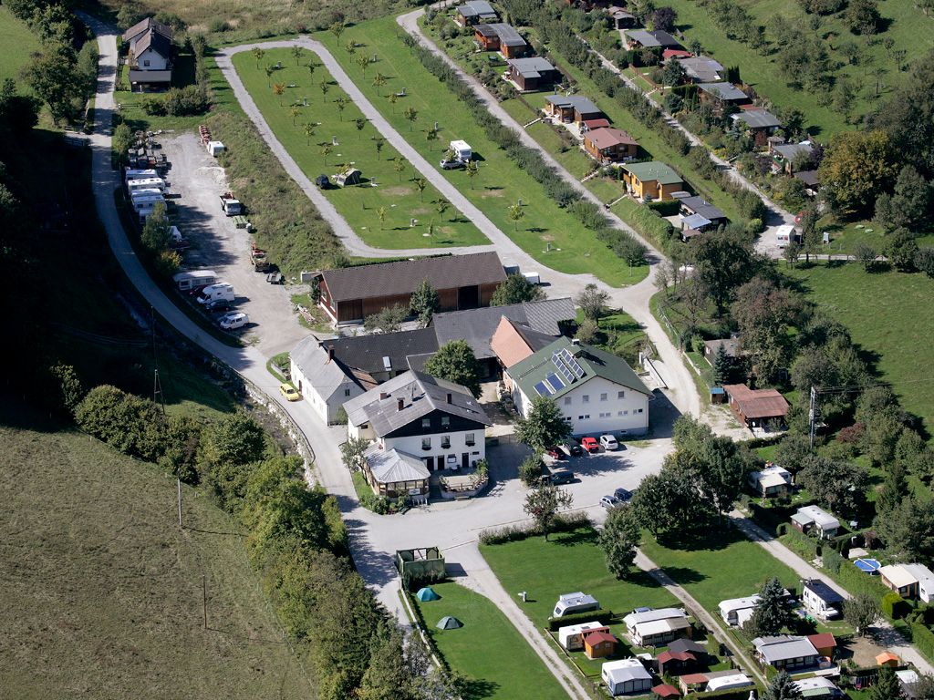 Letecký pohled na kemp s karavany a budovami v zelené krajině.