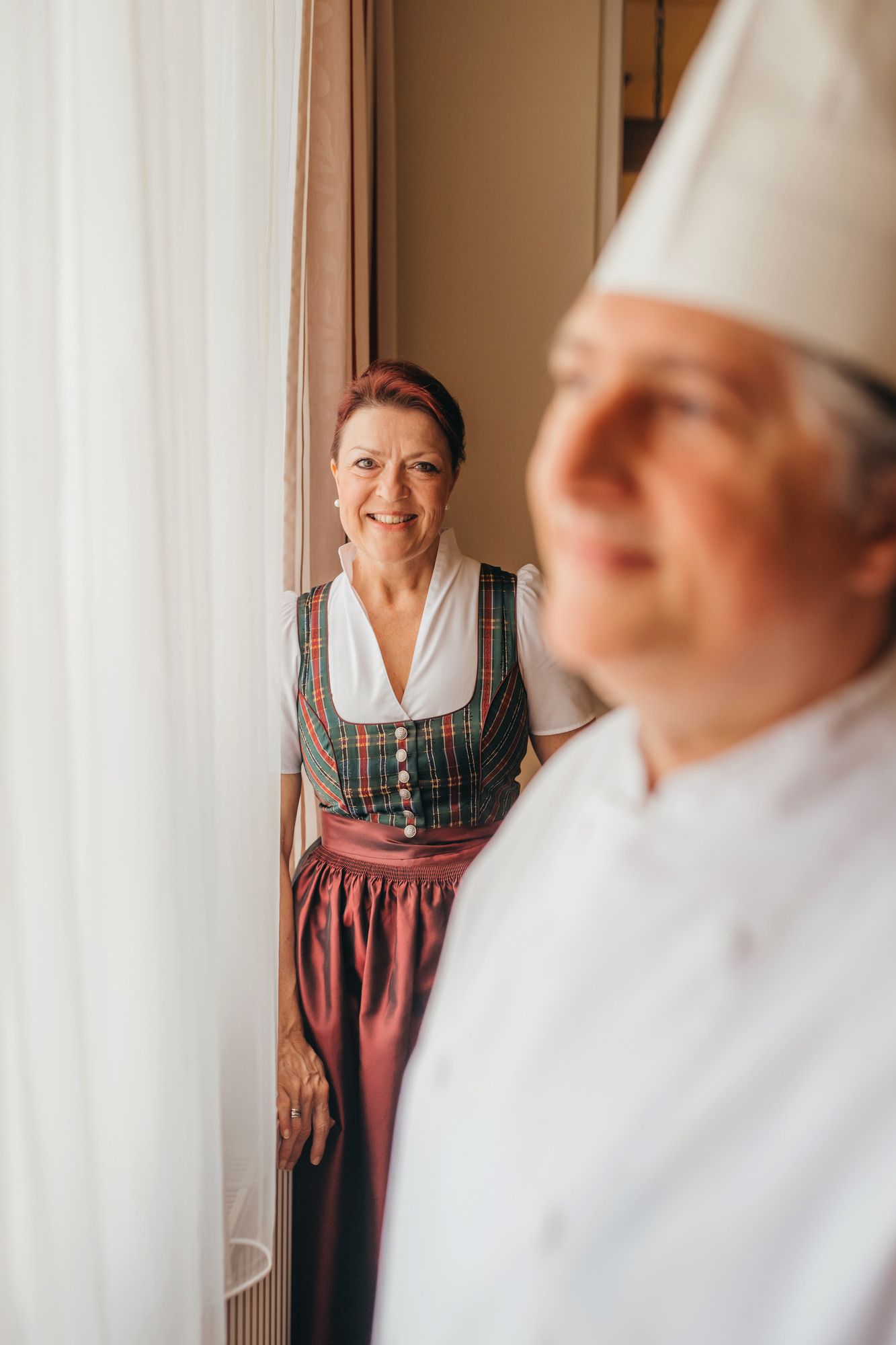 Žena v tradičním oděvu stojí vedle kuchaře v bílé uniformě.