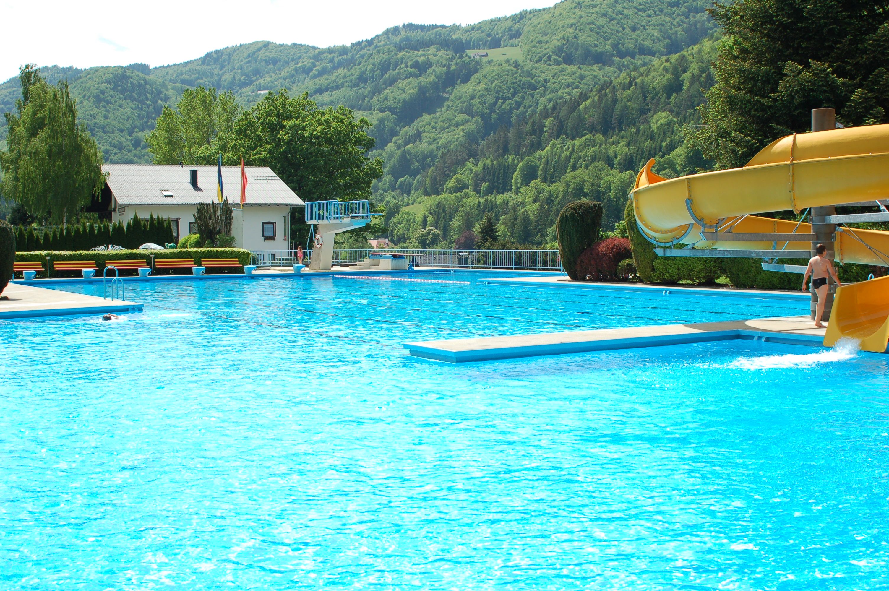 Venkovní bazén se skluzavkou, skokanským prknem a okolními horami.