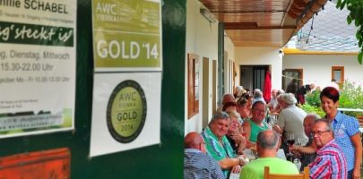 Lidé sedí u dlouhého stolu v zastřešeném venkovním prostoru restaurace.