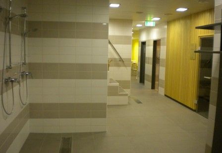 Pohled do interiéru sauny se sprchami a dřevěnými stěnami.