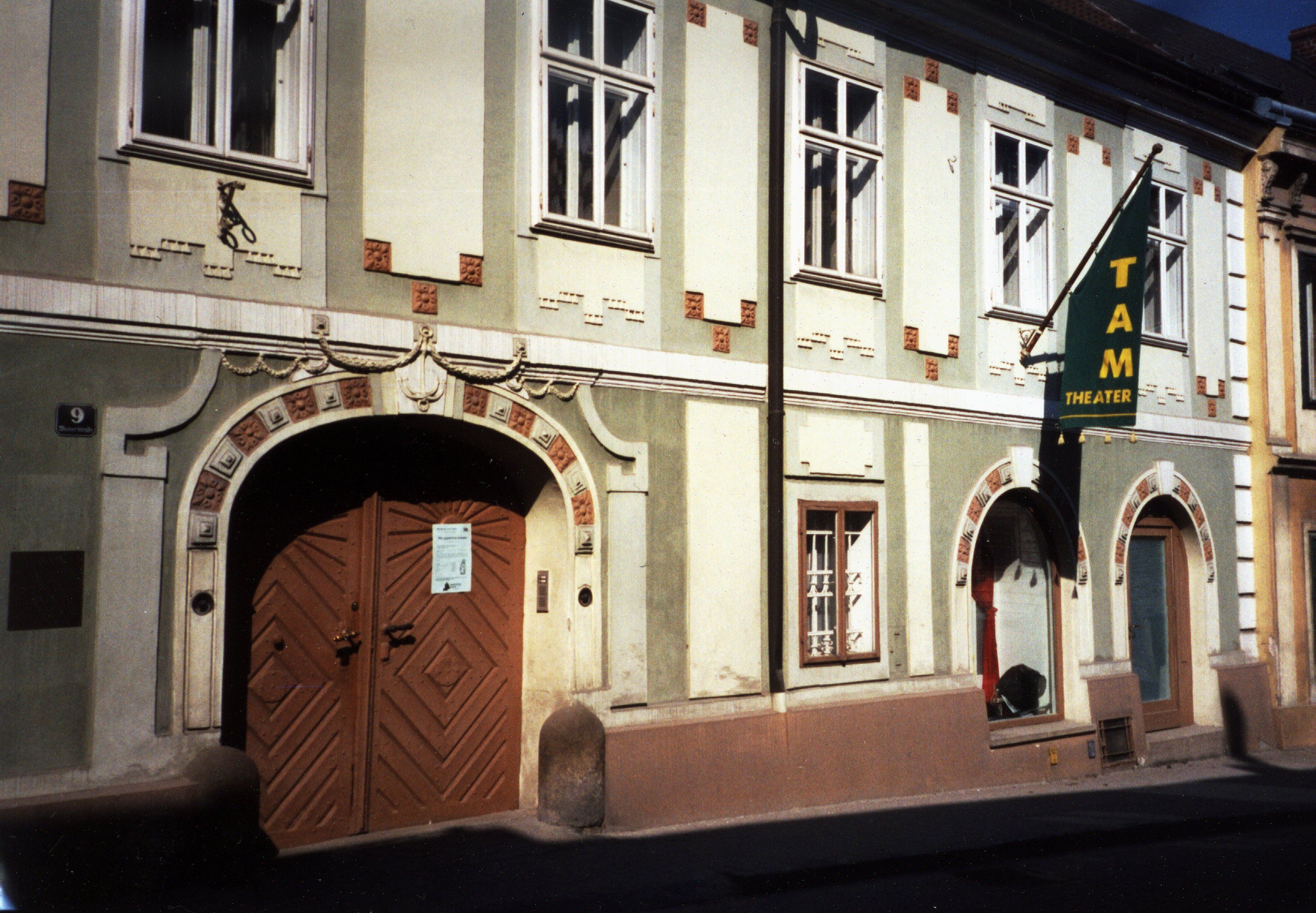 Průčelí TAM - Divadla na zdi se vstupními dveřmi a okny.