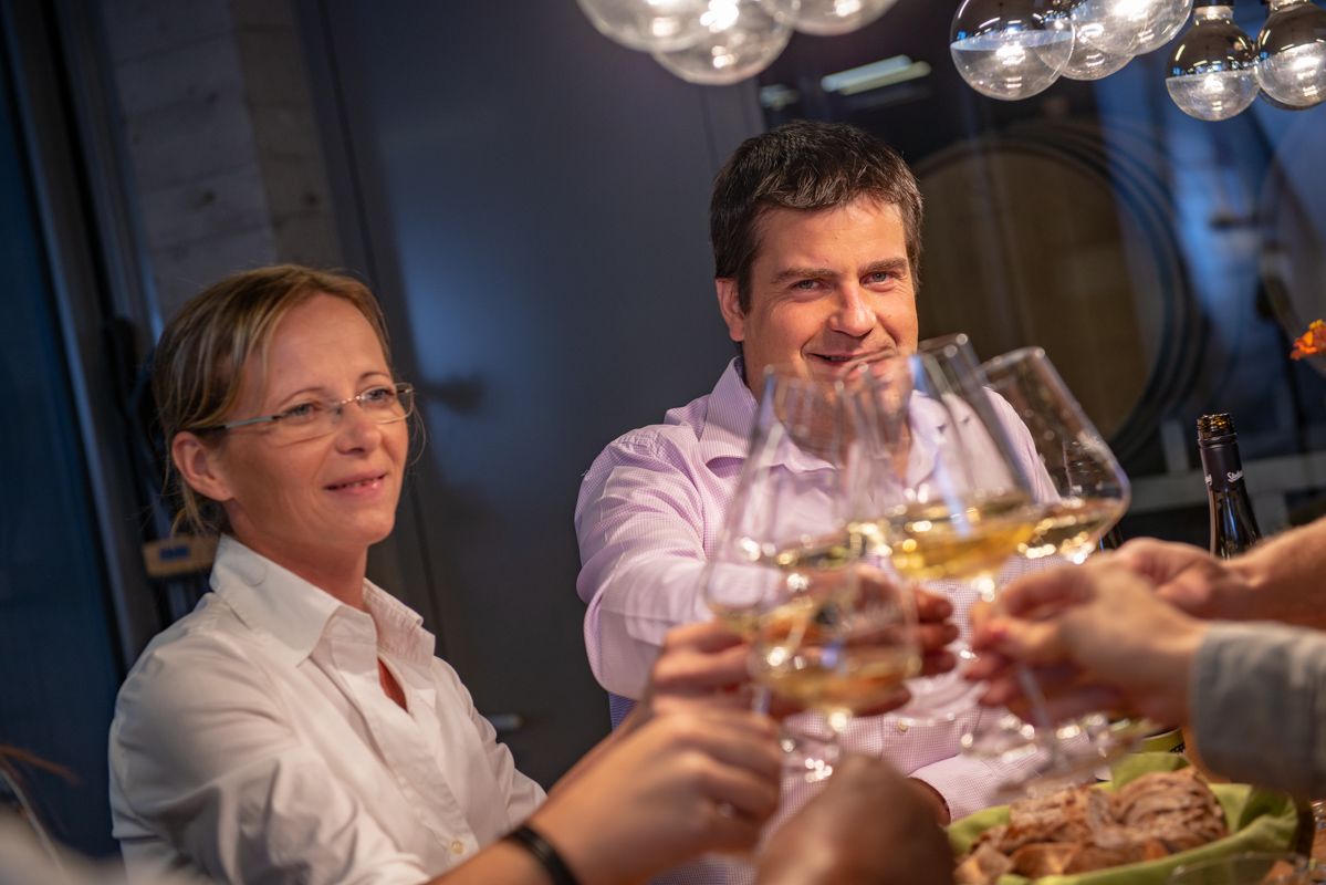 Lidé si u stolu cinknou skleničkami vína.