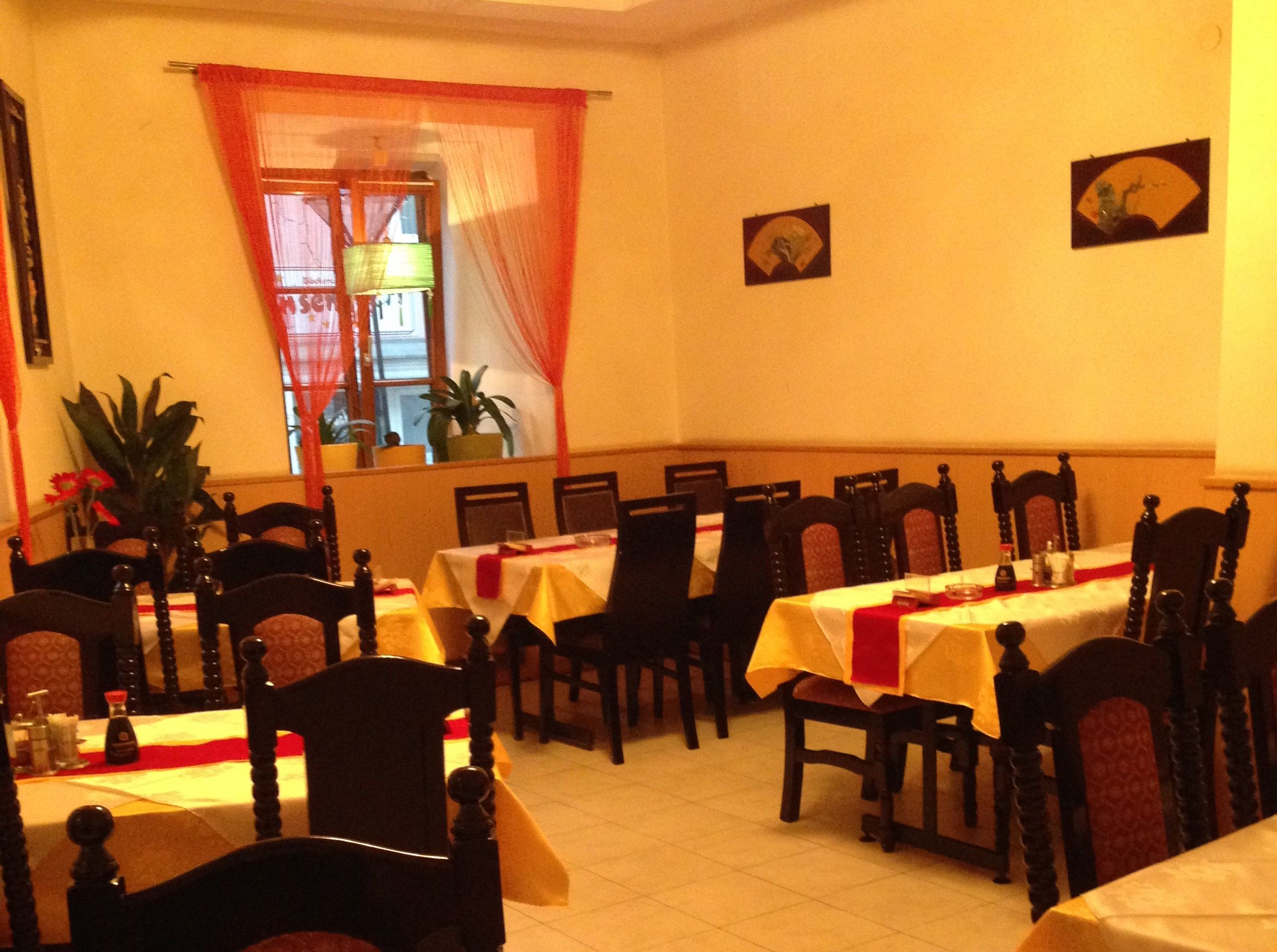 Pohled do interiéru asijské restaurace s prostřenými stoly a židlemi.