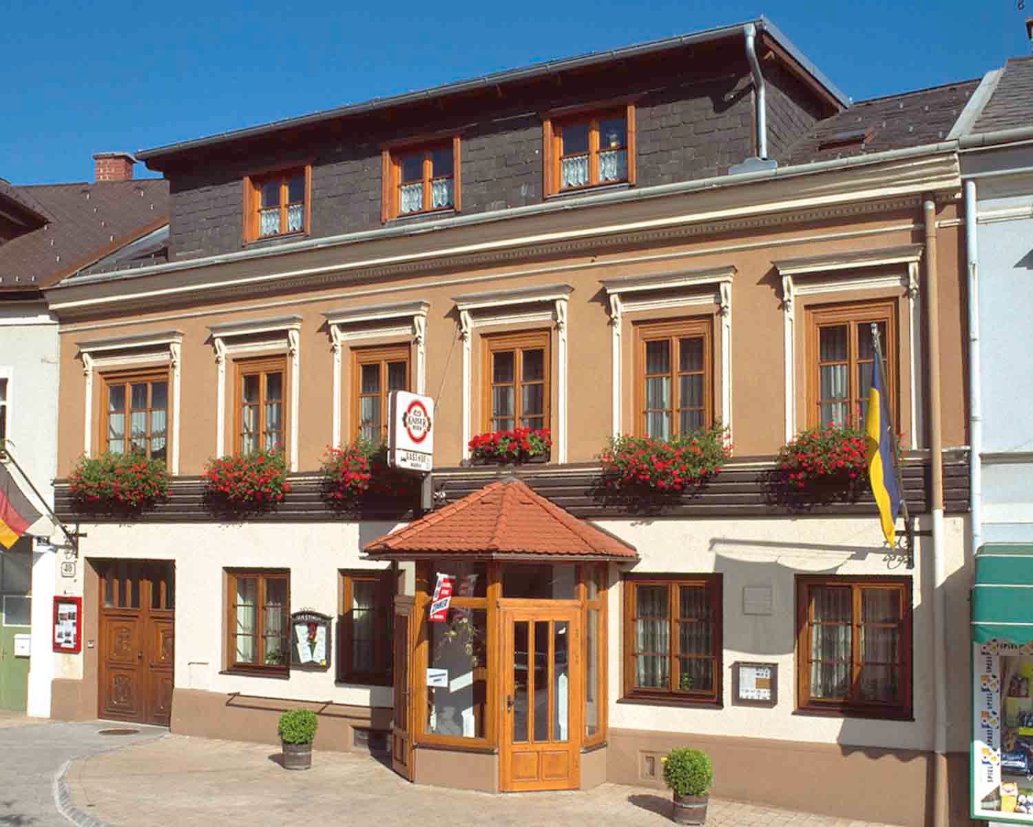 Tradiční hostinec s květinami a vlajkami.