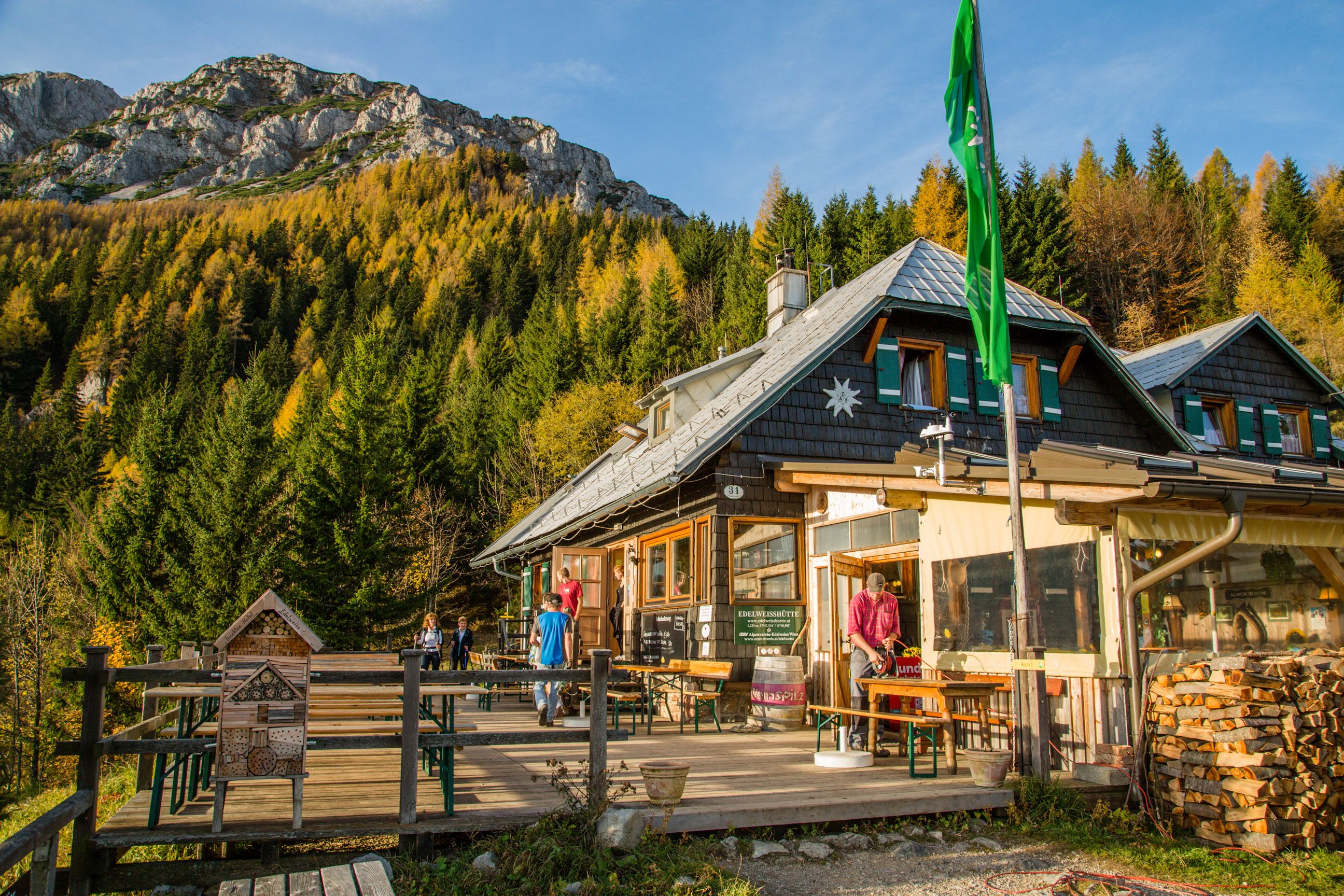 Chata Edelweiss na Schneebergu s horskou krajinou a lesem v pozadí.