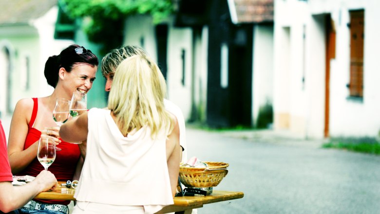 Lid&eacute; sed&iacute; u stolu ve sklepn&iacute;ch uličk&aacute;ch a pij&iacute; v&iacute;no.