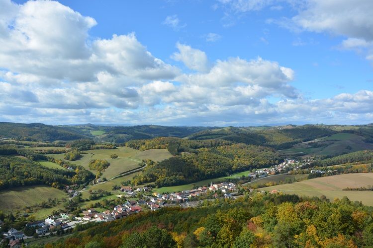 Krajina s kopci, lesy a vesnicí na podzim.