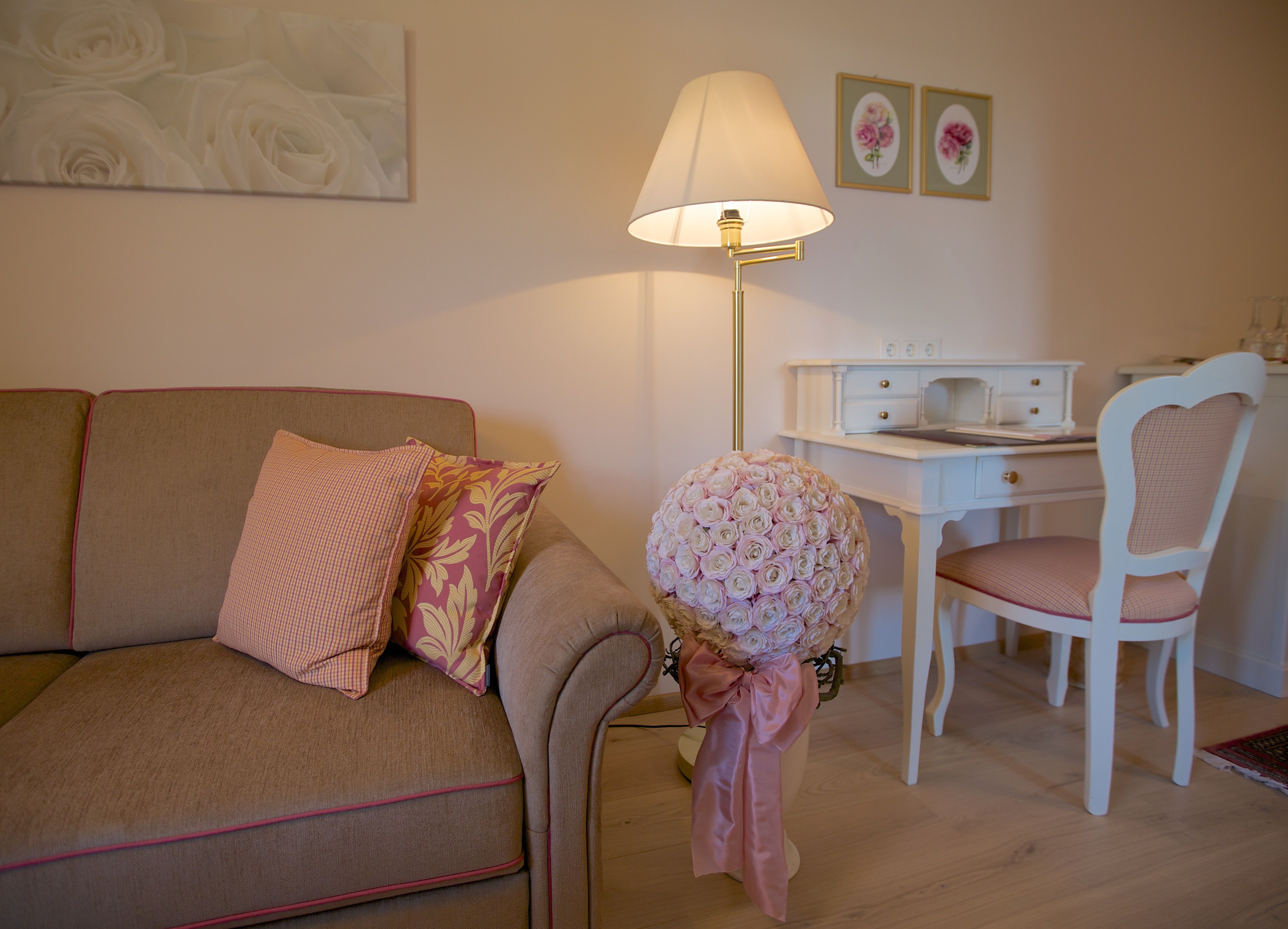 Útulný obývací pokoj s pohovkou, psacím stolem a květinovou výzdobou.