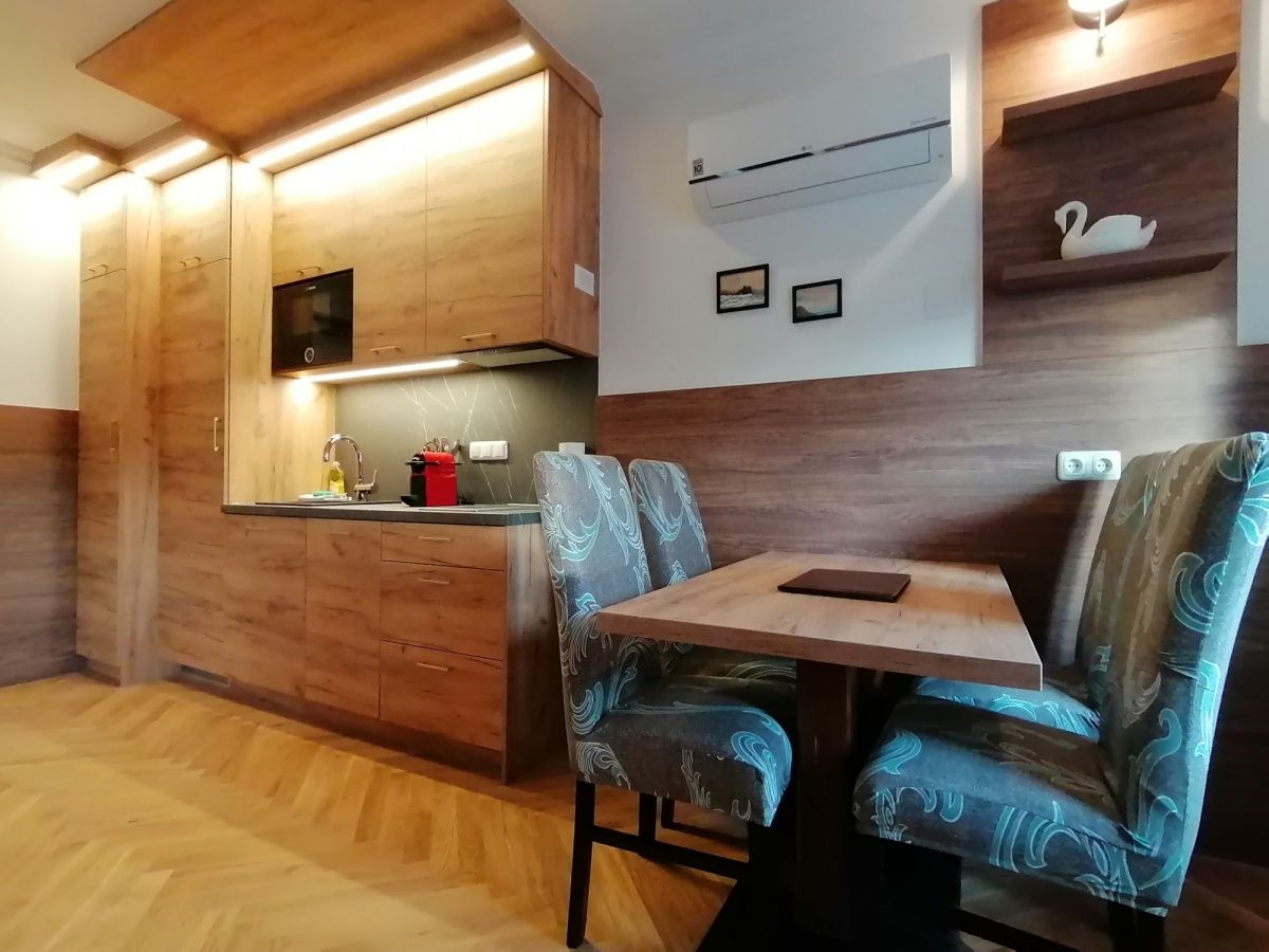 Moderní kuchyně s dřevěným nábytkem a jídelním stolem v bytě.