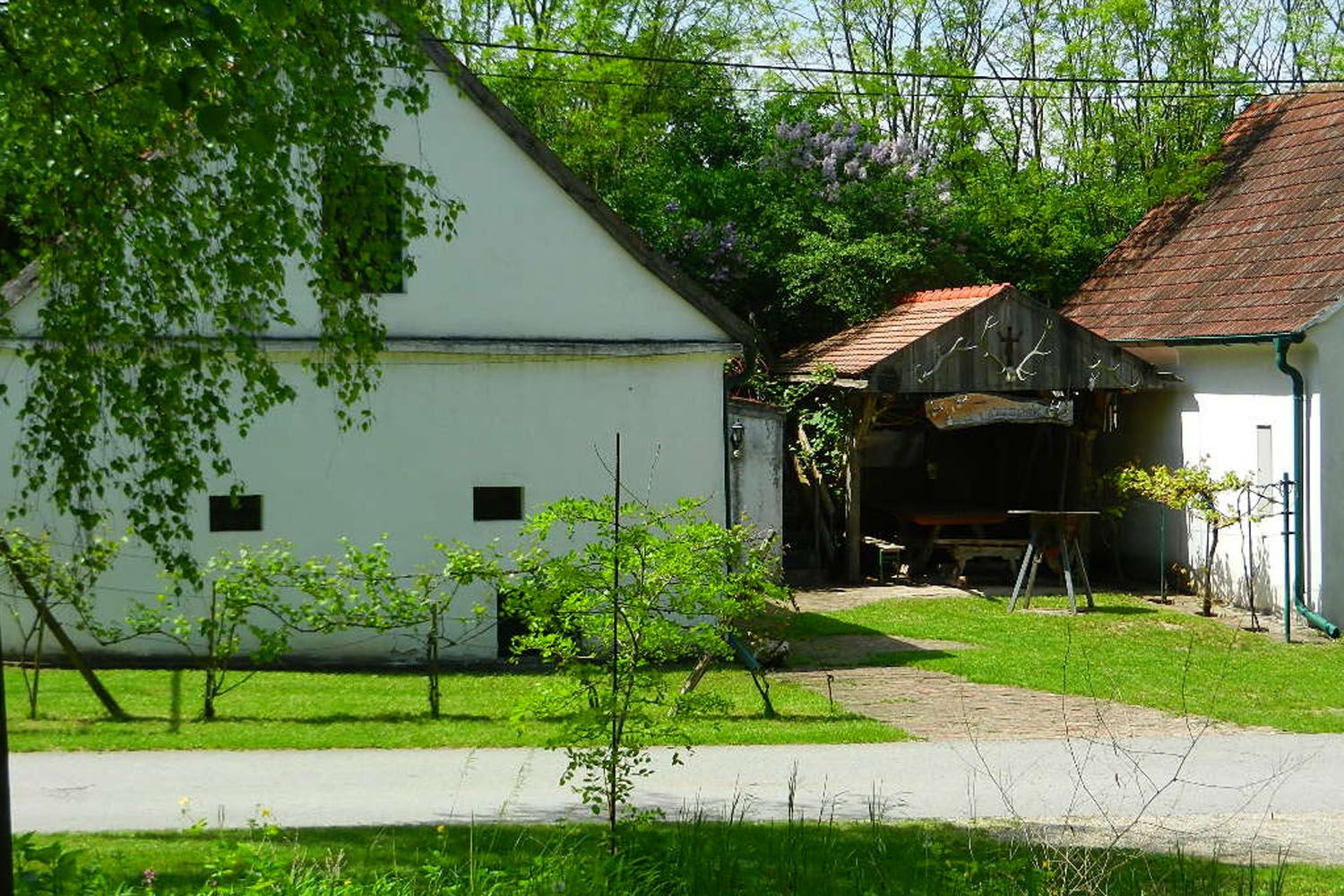 Venkovský dvůr s bílými budovami a zelenou zahradou.