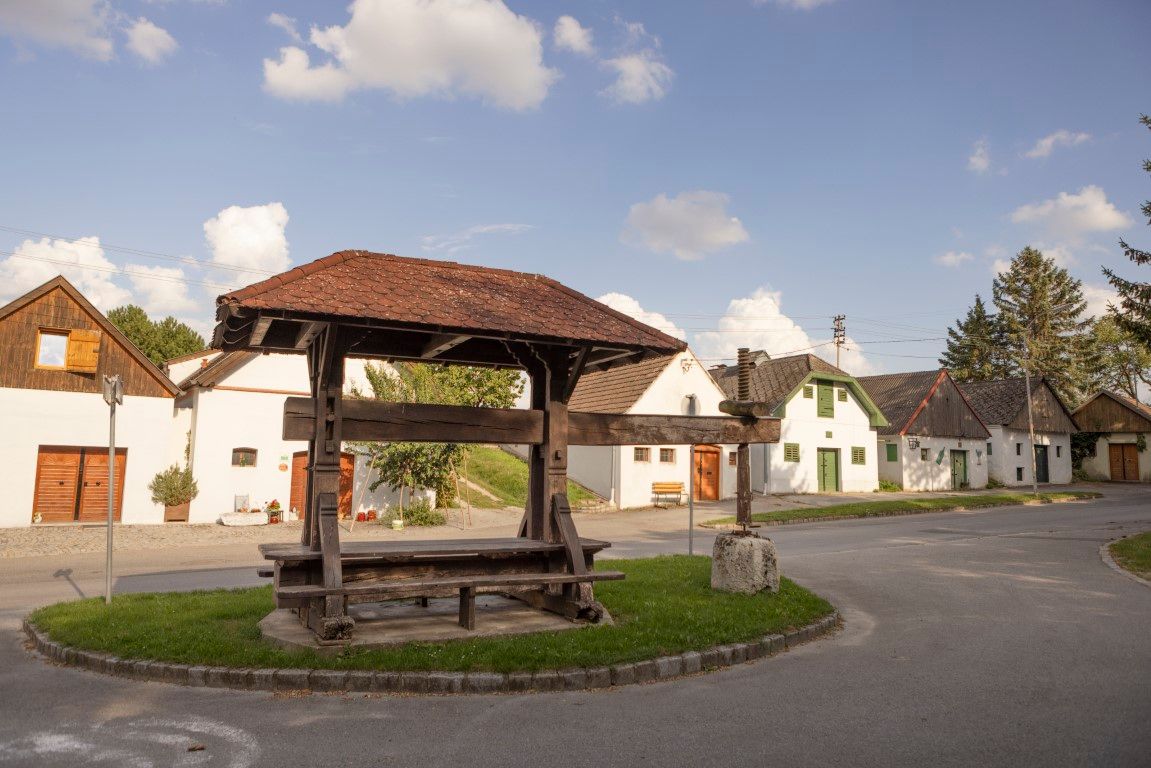 Historický lis na víno v Kettlasbrunnu před tradičními domy ve sklepní uličce.