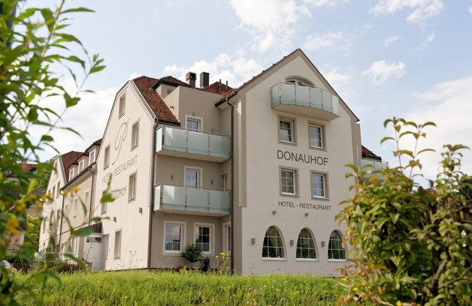 Pohled zvenč&iacute; na hotel Restaurant Donauhof s balkony a zahradou.