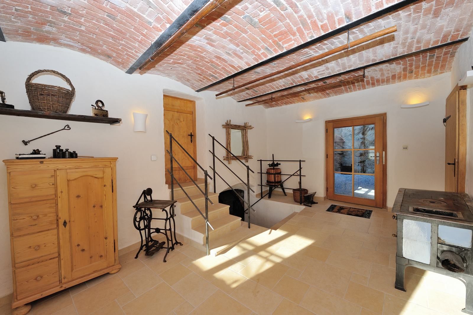 Interiér s klenutým stropem, dřevěným nábytkem a starožitnými předměty.