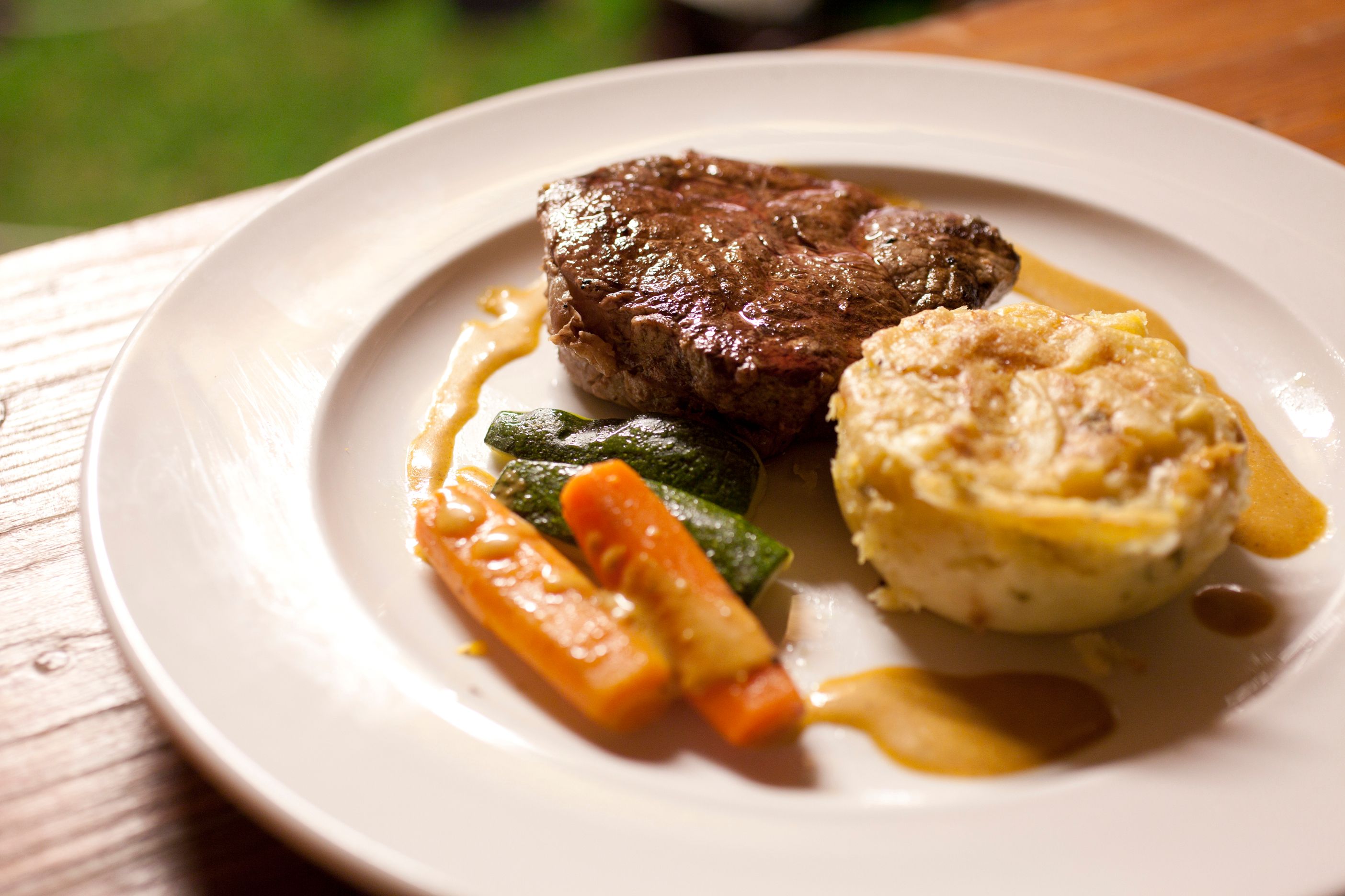 Talíř s kouskem masa, zeleninou a gratinovanými bramborami.