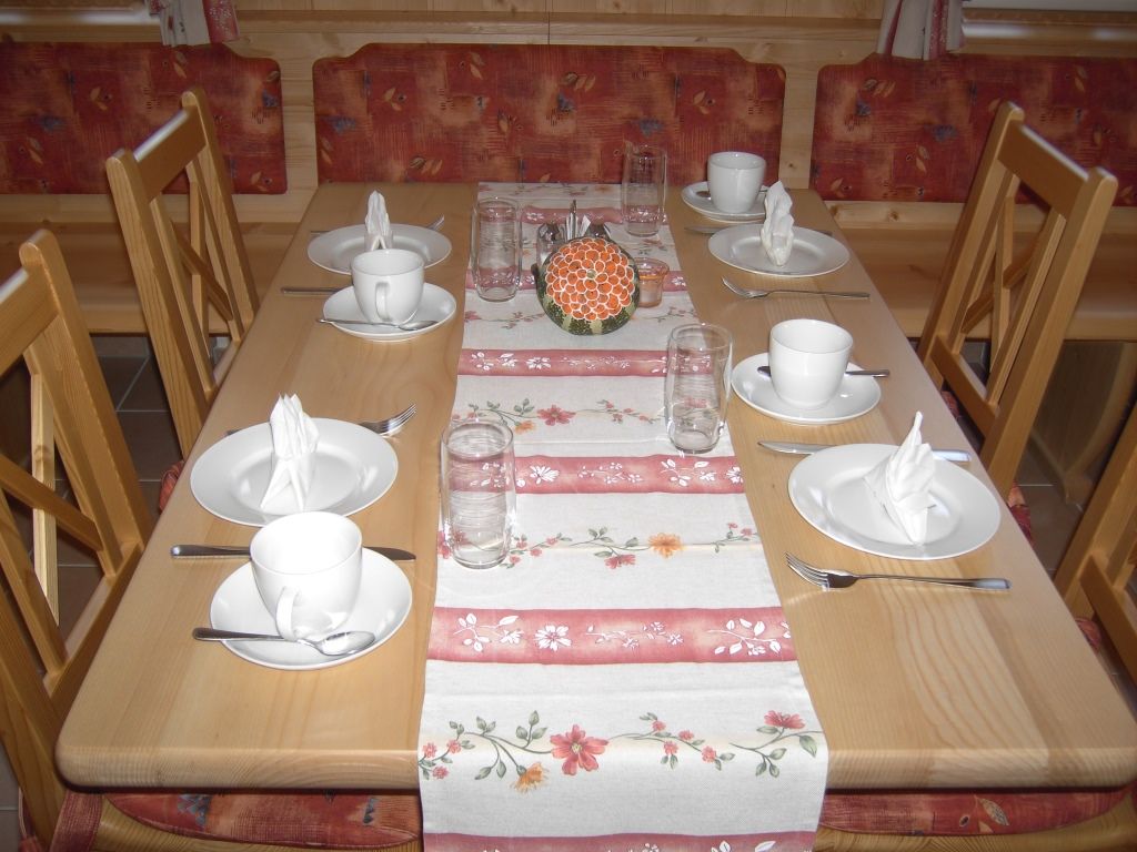 Prostřený stůl v jídelně s nádobím a sklenicemi.