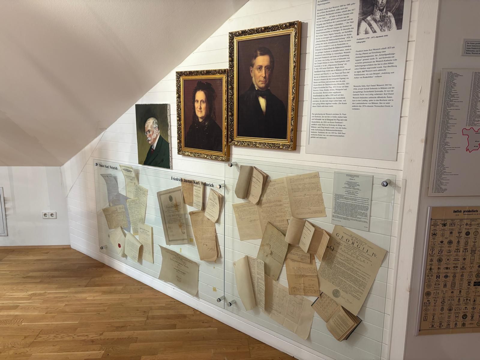 Výstava v Muzeu cukru s portréty a historickými dokumenty na stěně.