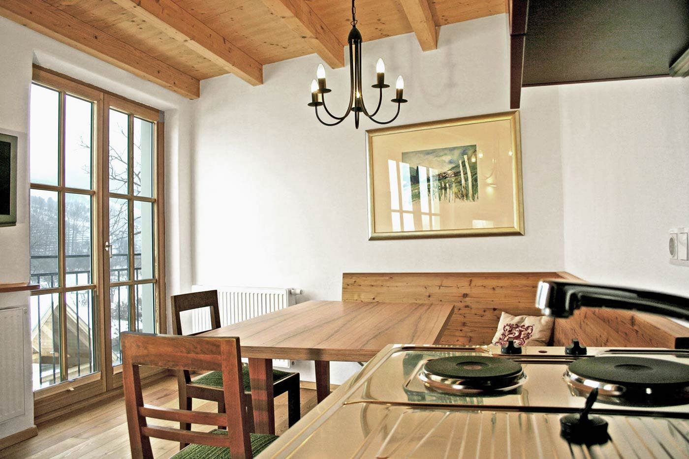 Útulný pokoj pro hosty s dřevěným nábytkem a kuchyňským koutem.