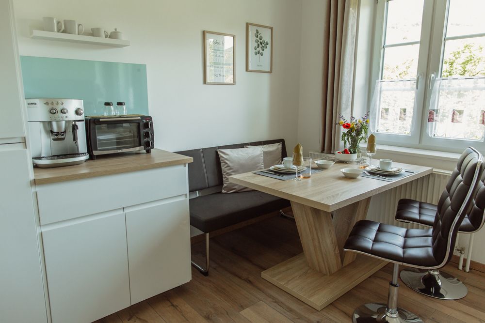 Moderní kuchyně s jídelním stolem, židlemi a kávovarem.