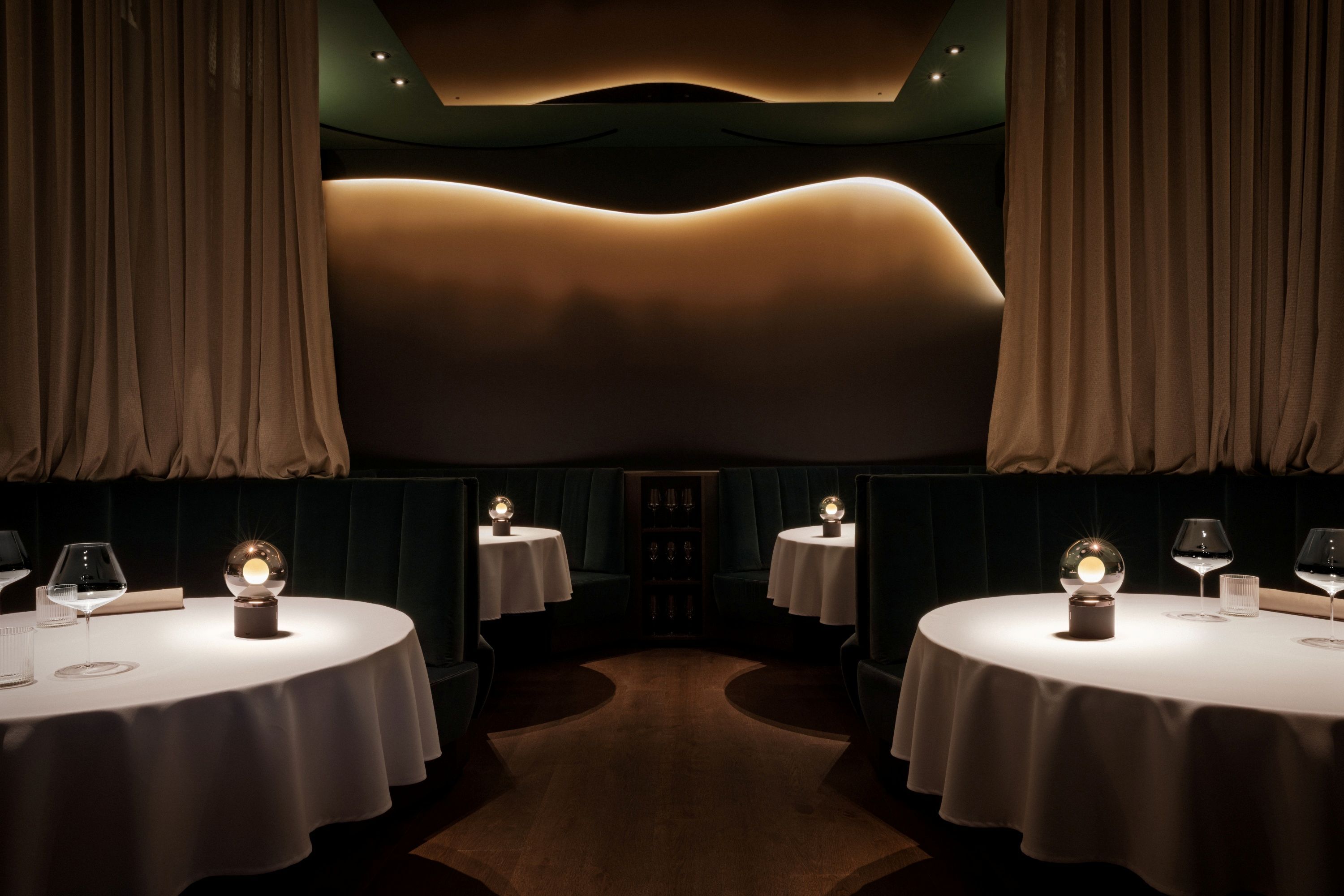 Elegantní restaurace s kulatými stoly, bílými ubrusy a tlumeným osvětlením.