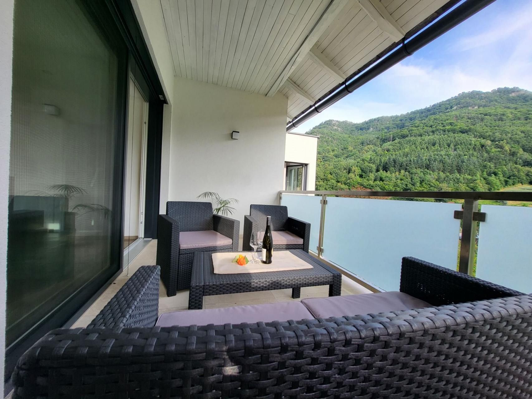 Balkon s ratanovým nábytkem a výhledem na hory.