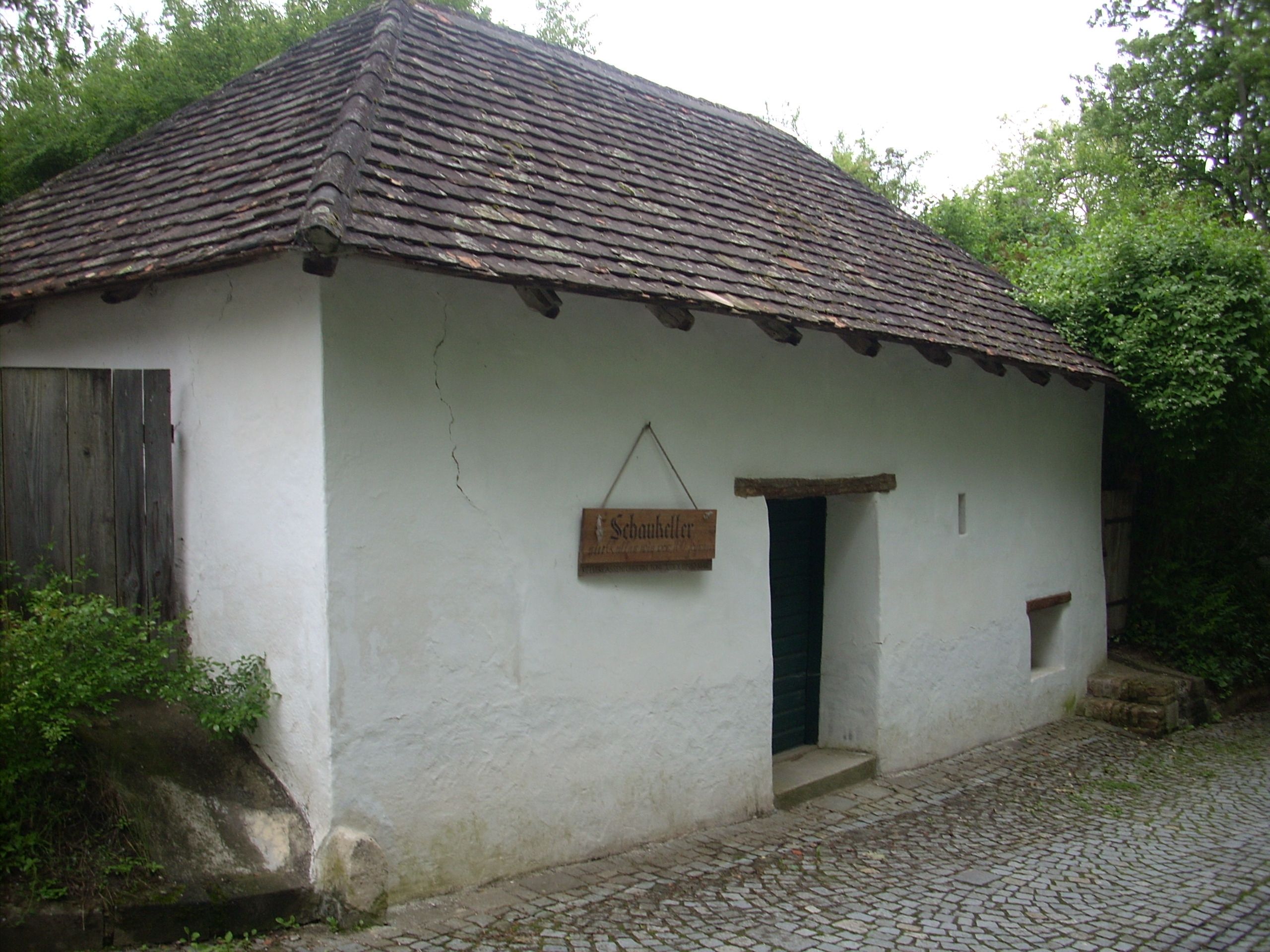 Tradiční budova s bílou fasádou a taškovou střechou s označením "Schaukeller".