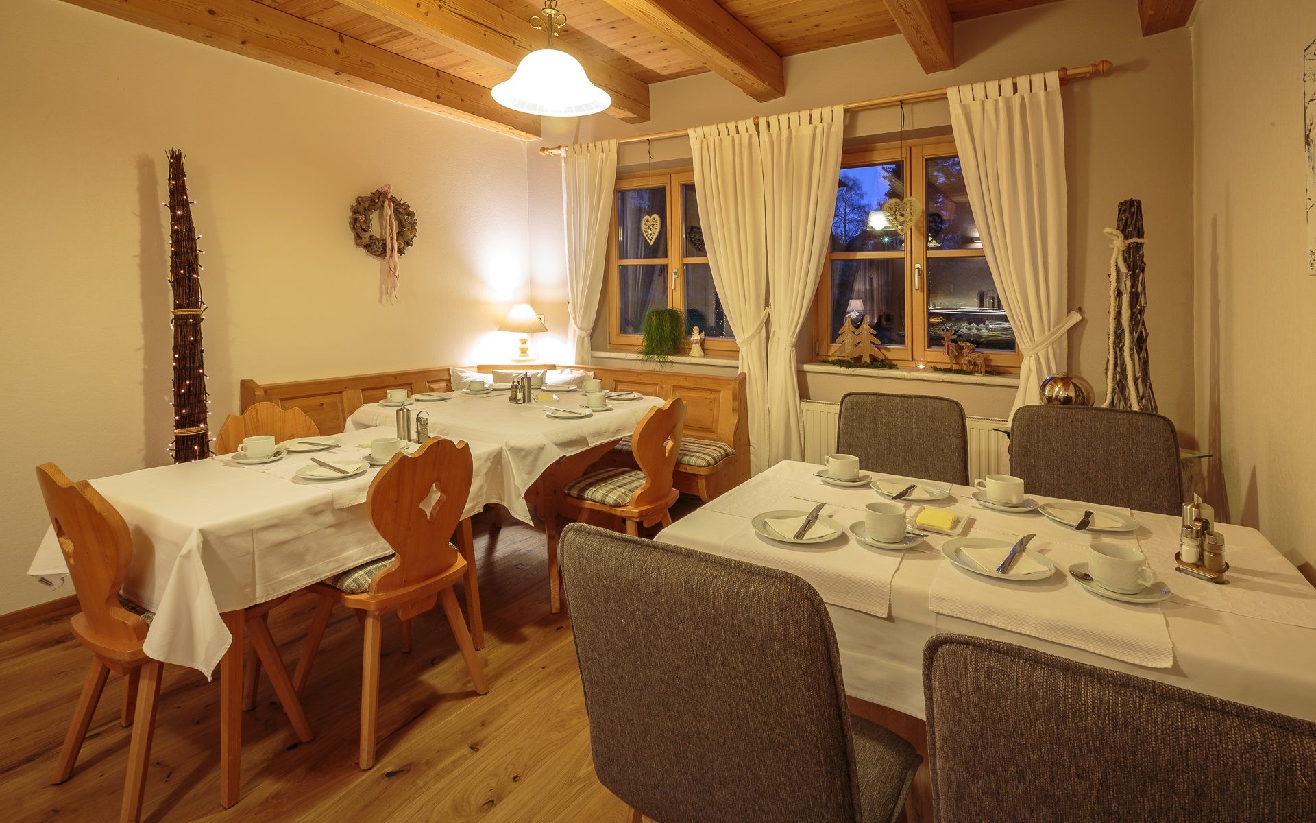 Útulná snídaňová místnost s prostřenými stoly, dřevěným nábytkem a dekoracemi.