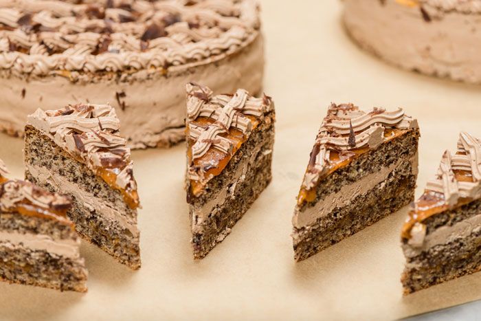 Detailní záběr na nakrájené kousky čokoládového dortu s krémem a čokoládovou polevou.