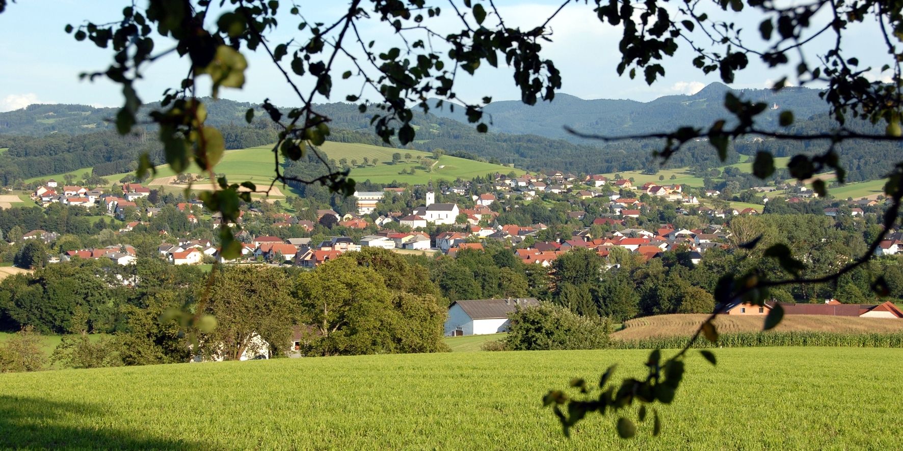 Panorama Oberndorfu an der Melk se zelenými poli a kopci v pozadí.