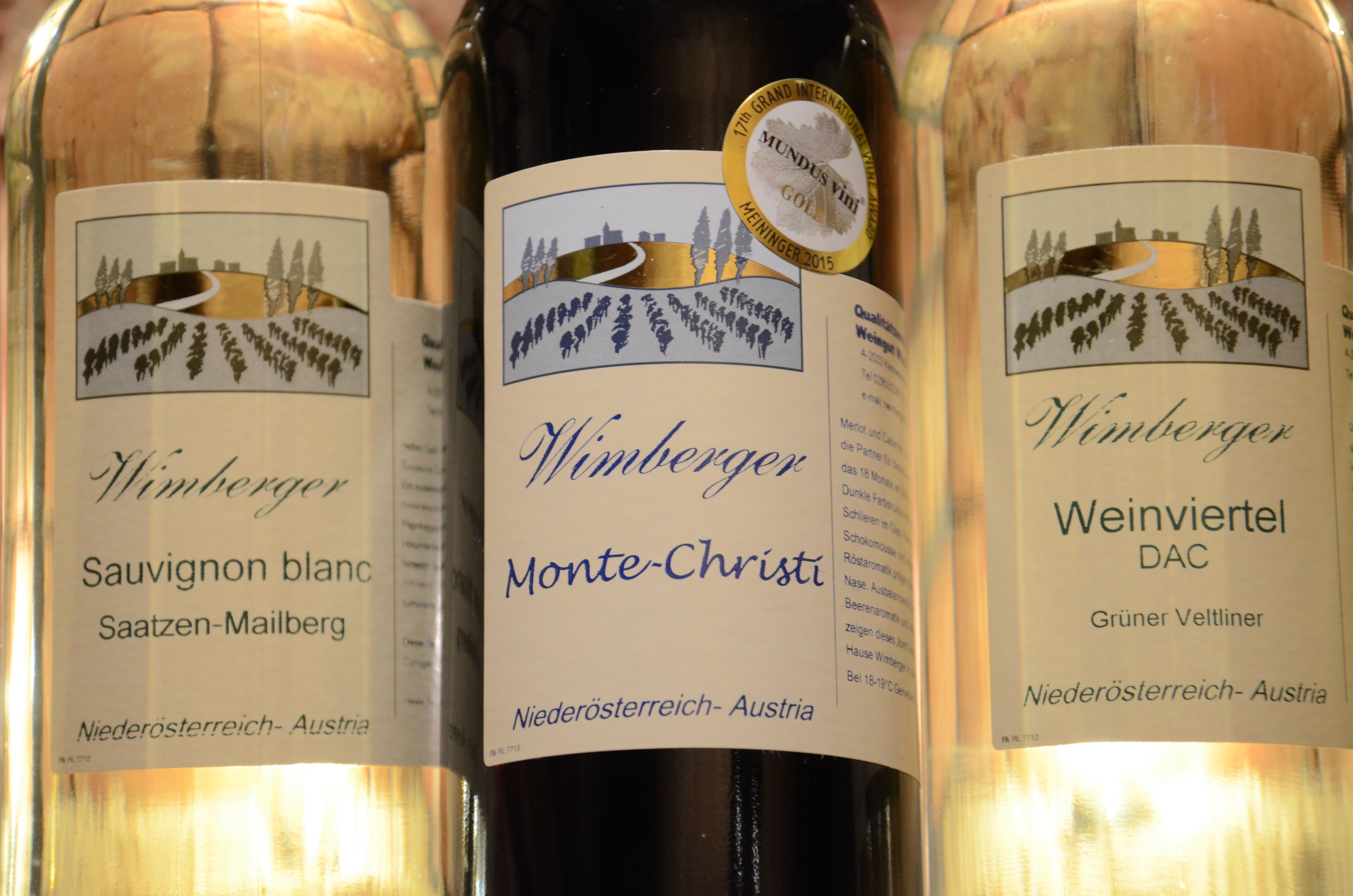 Tři láhve vína značky Wimberger s etiketami Sauvignon Blanc, Monte-Christi a Weinviertel DAC.