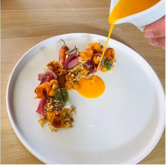 Detailní záběr na připravovaný pokrm z čerstvých surovin; kvalitní prezentace v prostředí moderní restaurace.