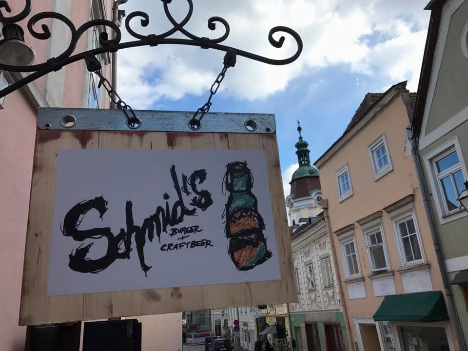 Nápis Schmid's Burger and Craftbeer na zdi domu ve staroměstské ulici.