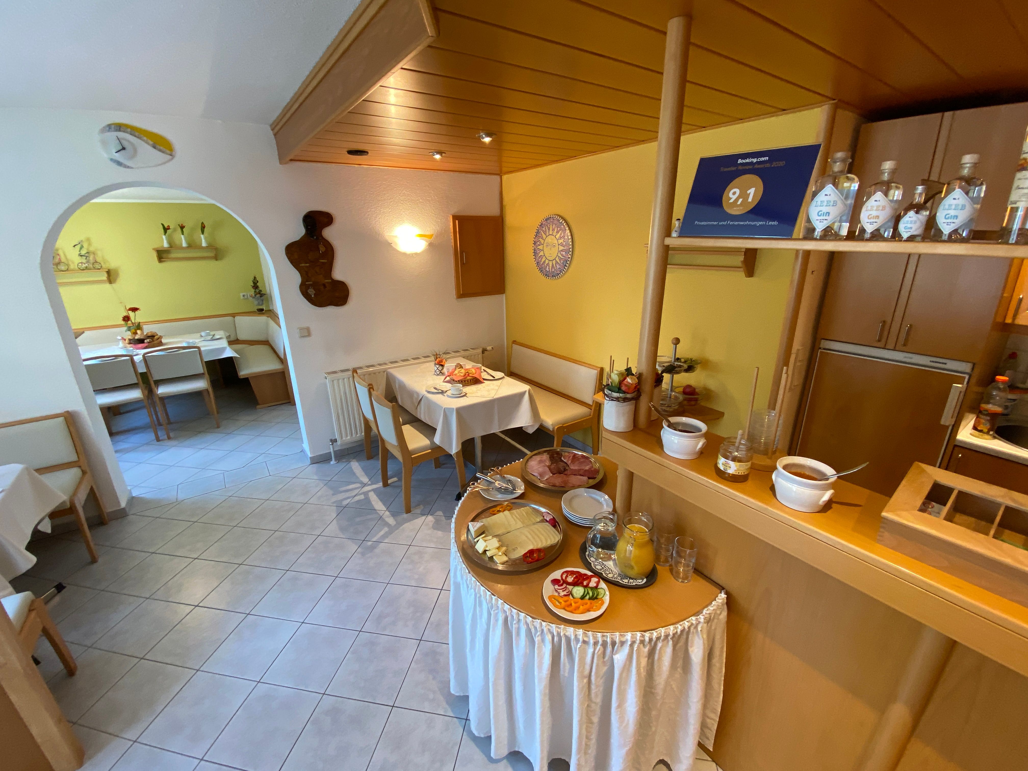 Snídaňová místnost s prostřenými stoly a snídaňovým bufetem.