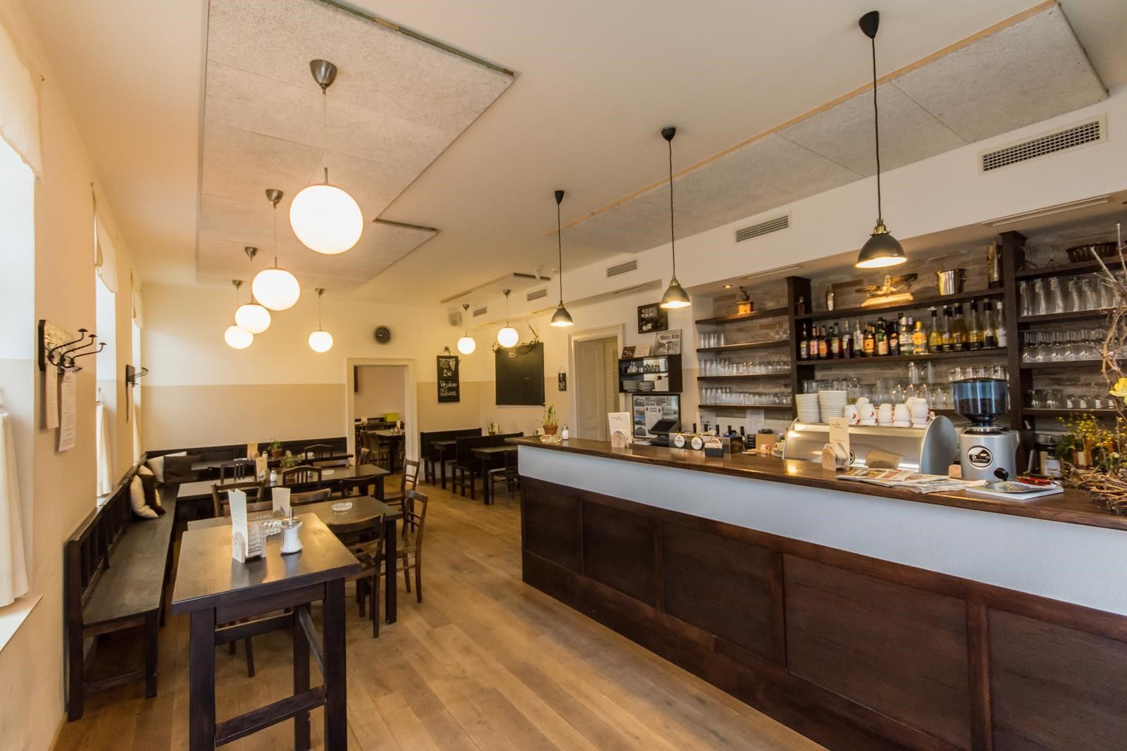 Pohled do interiéru útulné hospůdky s dřevěným nábytkem a barem.