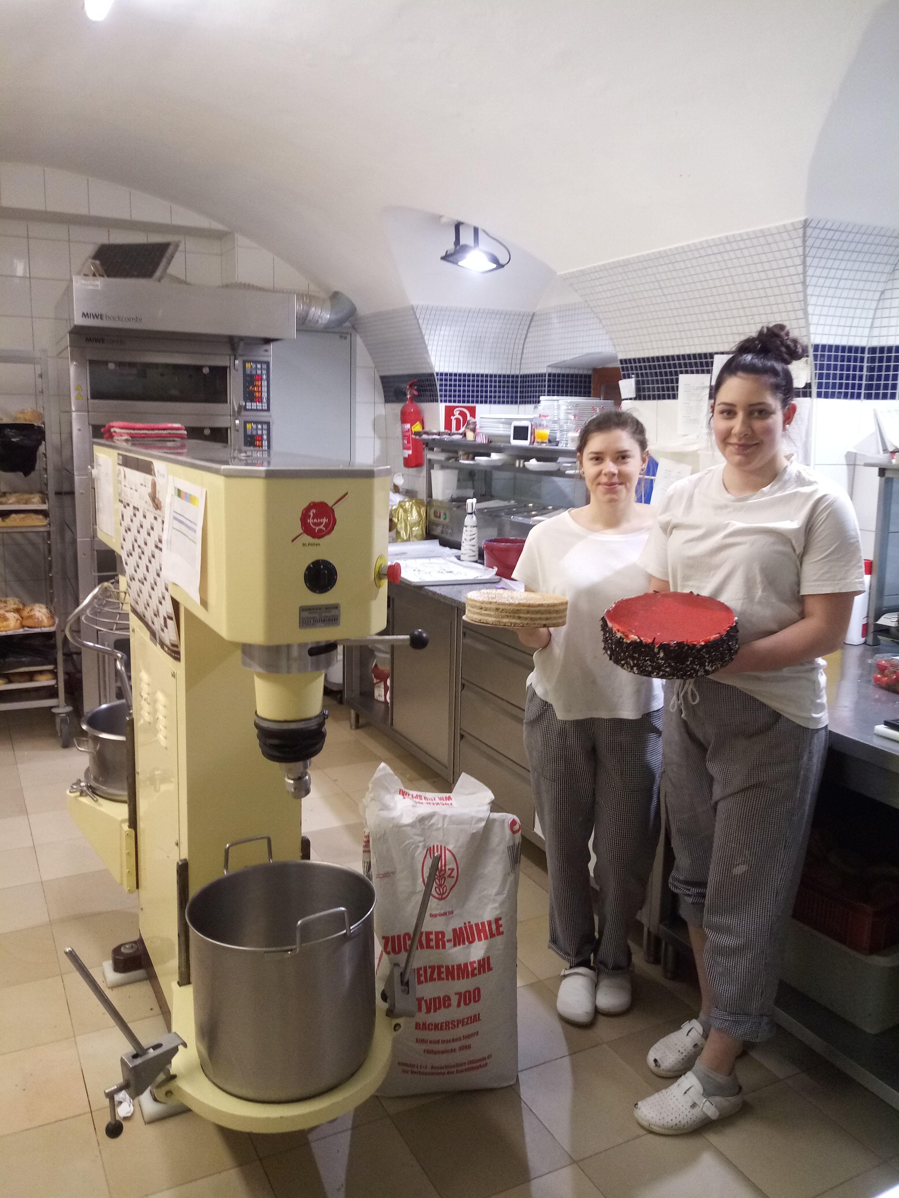 Dva lidé v pekárně s dortem a dortovým základem.