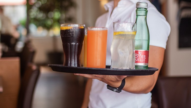 Usměvav&aacute; serv&iacute;rka pod&aacute;v&aacute; n&aacute;poje na t&aacute;cku v &uacute;tuln&eacute; restauraci.