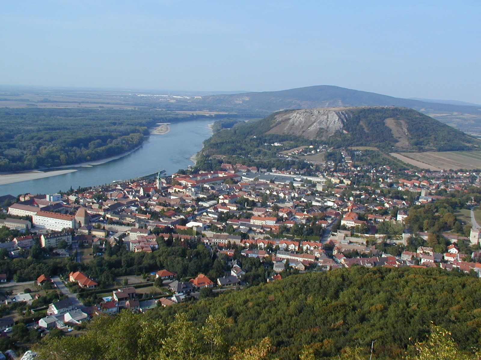 Panoramatický pohled na město s řekou a kopci v pozadí.