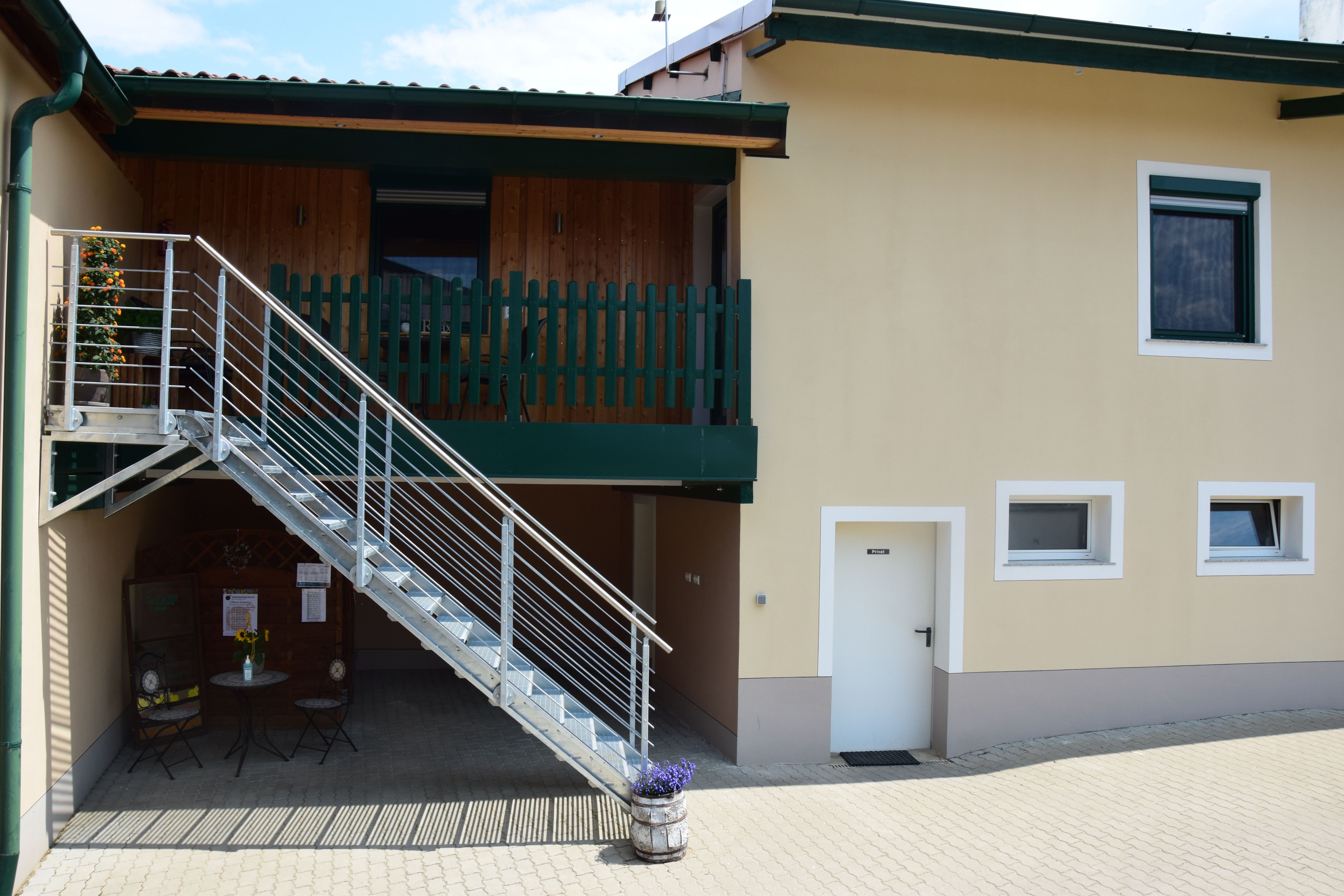 Pohled zvenčí na budovu se schodištěm a balkonem.