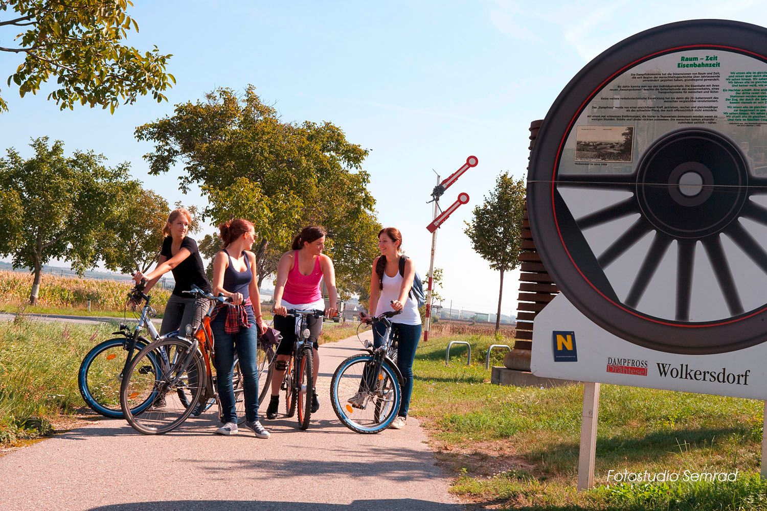 Čtyři ženy s koly na Cyklostezkách vedle velkého cyklistického památníku ve Wolkersdorfu.